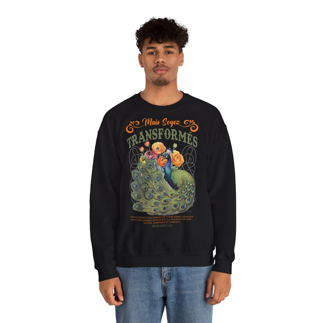 Un homme porte un sweat-shirt noir avec un paon et le texte biblique Mais soyez transformés.