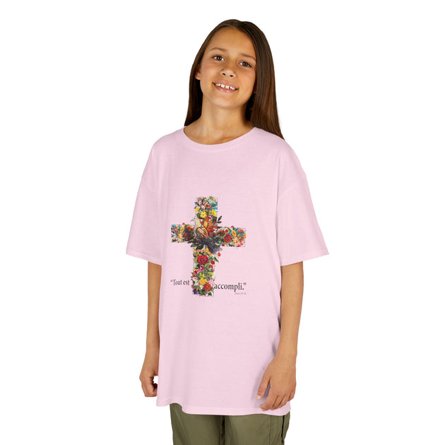 Une jeune fille porte un t-shirt rose orné d'une croix fleurie et de l'inscription Tout est accompli.