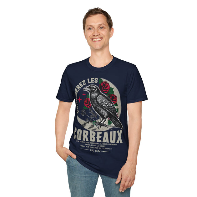 Un homme porte un t-shirt bleu marine illustré d'un corbeau, de roses et du verset Luc 12:24.