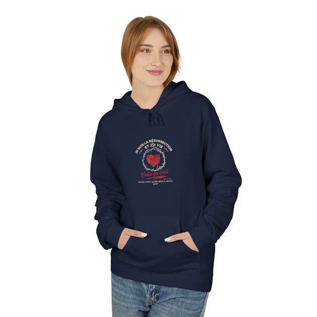Une femme porte un sweat à capuche bleu marine avec un motif religieux centré sur la poitrine.