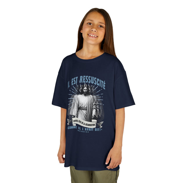 Une jeune fille porte un t-shirt bleu marine avec une illustration religieuse et du texte en blanc.