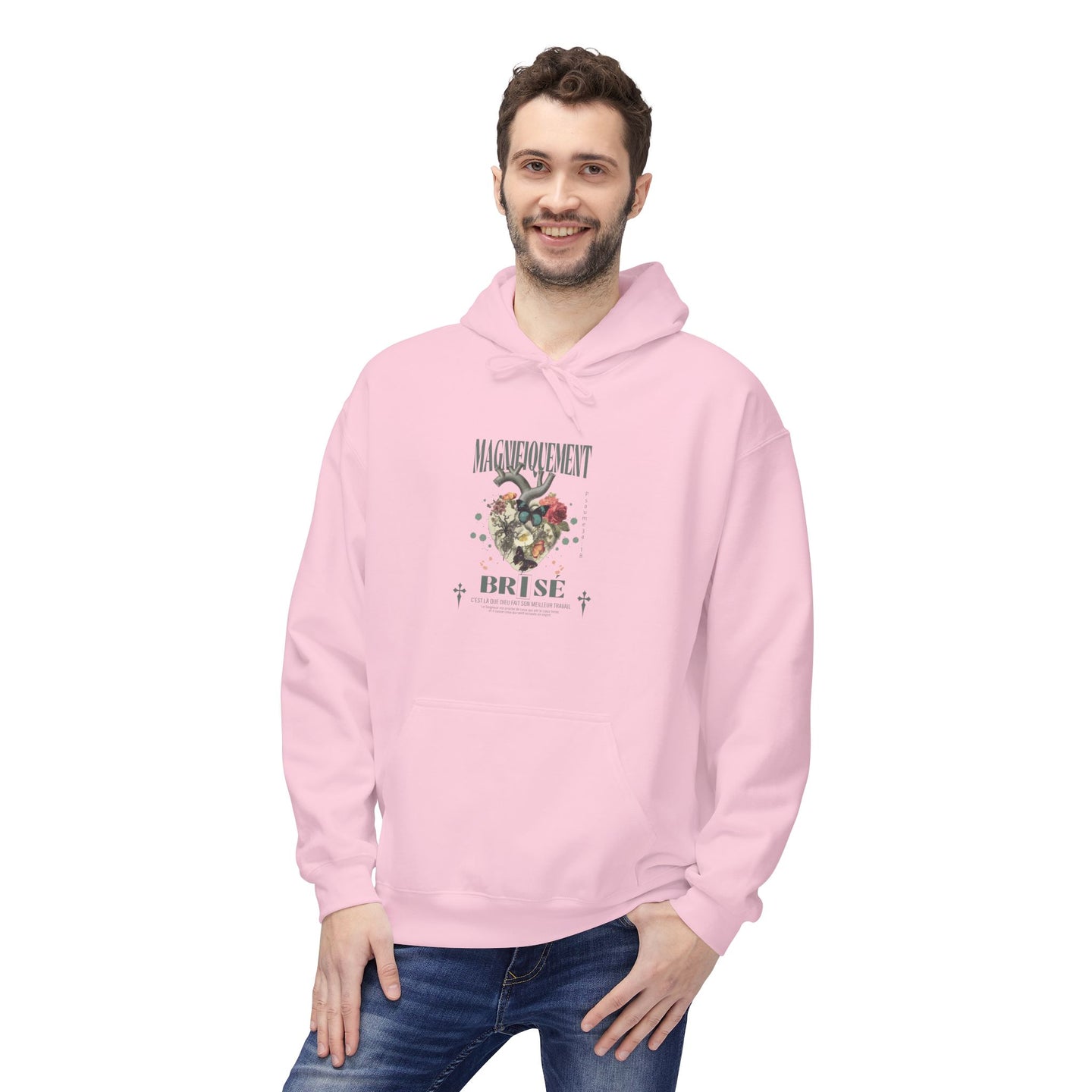 Un homme porte un sweat à capuche rose avec un motif floral en forme de cœur sur la poitrine.