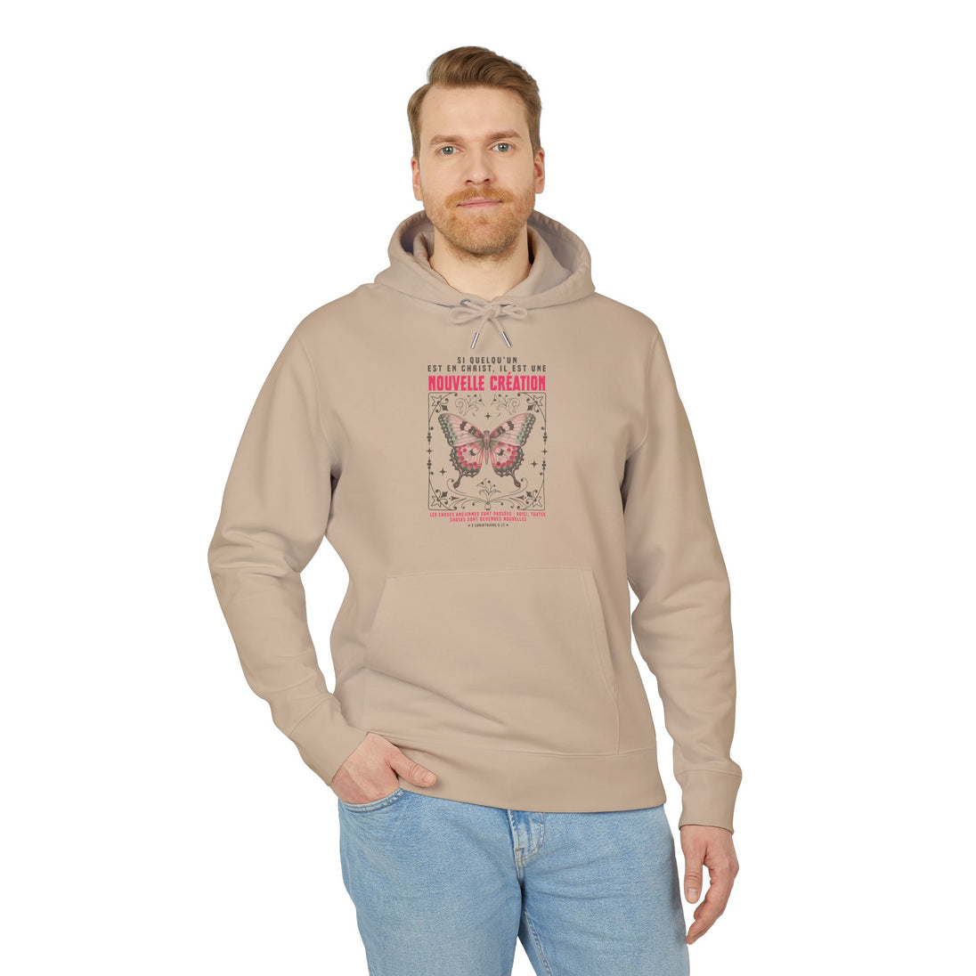 Un homme porte un sweat à capuche beige avec un motif de papillon et un texte religieux.