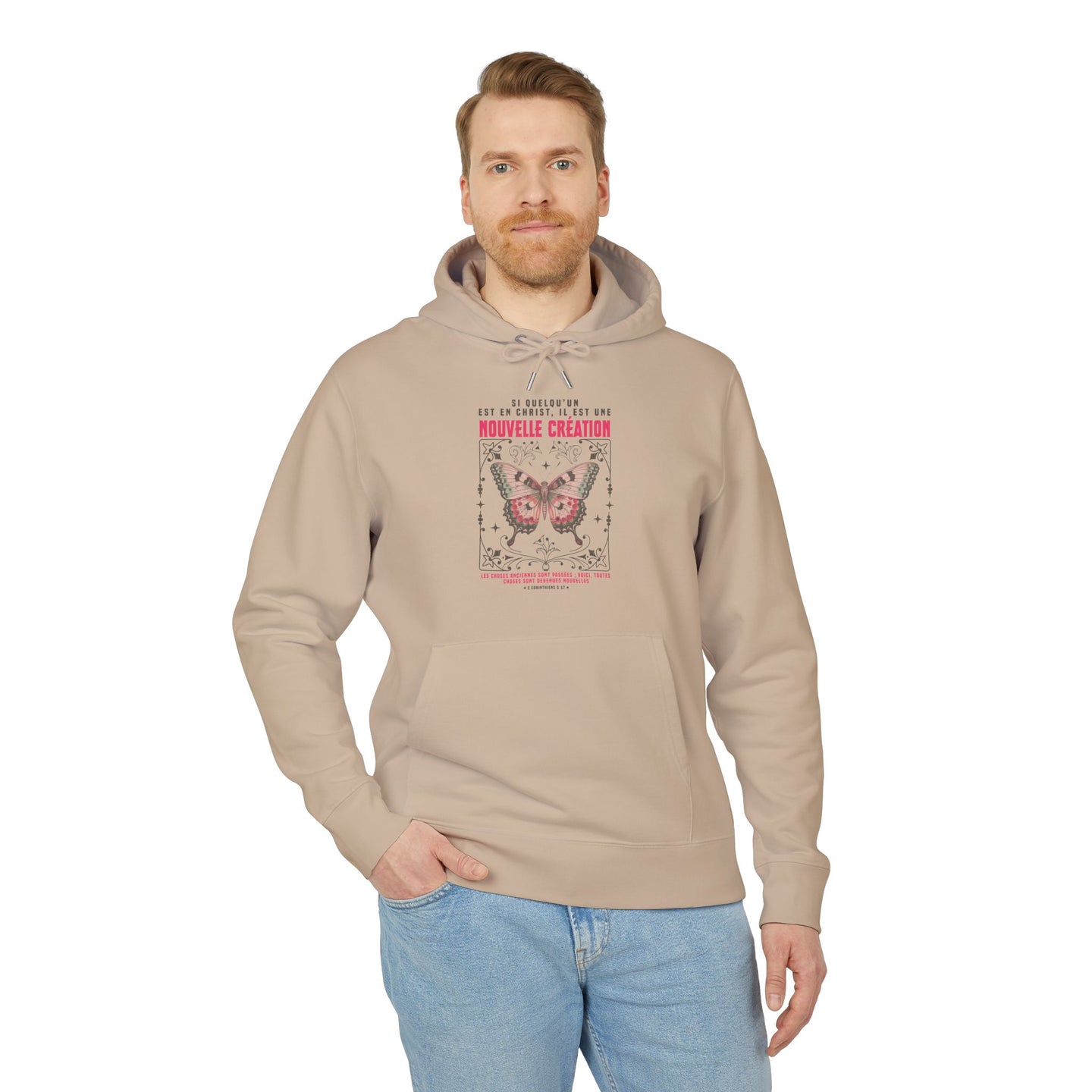 Un homme porte un sweat à capuche beige avec un motif de papillon et un texte religieux.