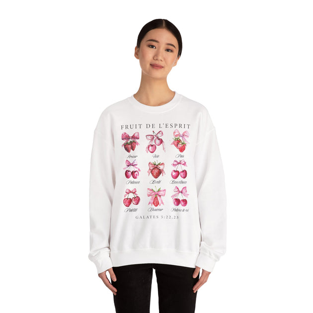 Une femme porte un sweat-shirt blanc orné d'illustrations de fruits et de textes en français.