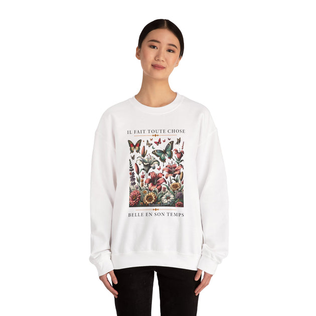 Une femme porte un sweat-shirt blanc orné d'un motif floral et de papillons avec une inscription.