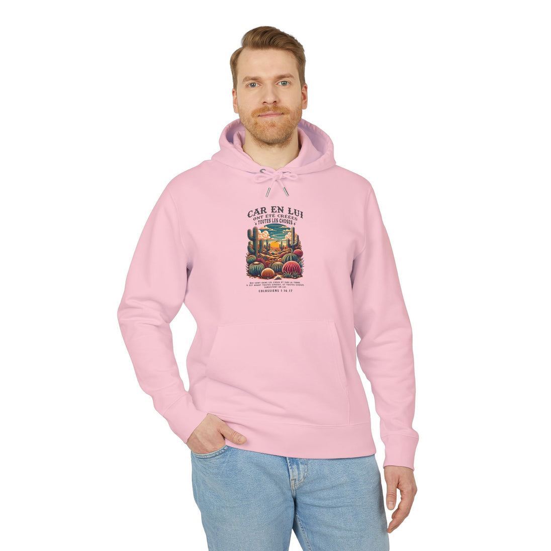 Un homme porte un sweat à capuche rose avec une illustration de désert et un verset biblique.