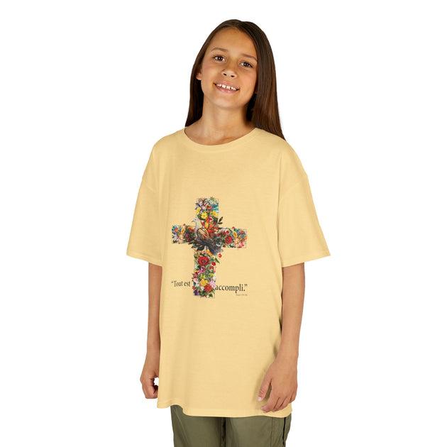 Une jeune fille porte un t-shirt jaune pâle orné d'une croix fleurie et de l'inscription Tout est accompli.