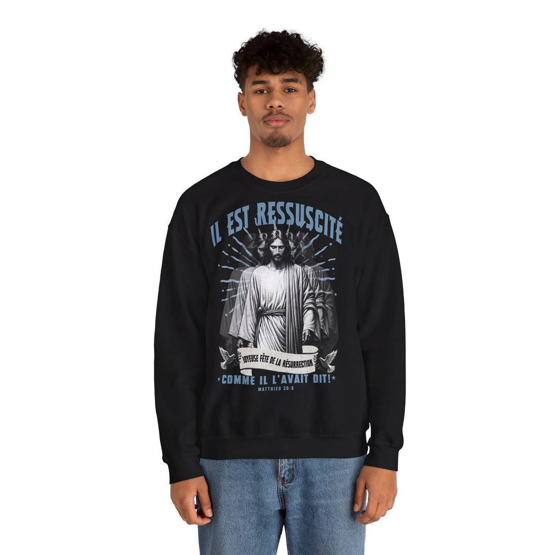 Un homme porte un sweatshirt noir avec une illustration religieuse et le texte Il est ressuscité.