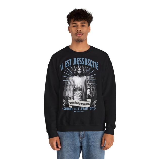 Un homme porte un sweatshirt noir avec une illustration religieuse et le texte Il est ressuscité.