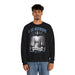 Un homme porte un sweatshirt noir avec une illustration religieuse et le texte Il est ressuscité.