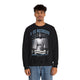 Un homme porte un sweatshirt noir avec une illustration religieuse et le texte Il est ressuscité.