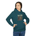Une femme porte un sweat à capuche bleu pétrole avec une illustration de paysage et du texte.