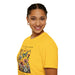 Une femme porte un t-shirt jaune orné d'un motif floral et de papillons avec une inscription.