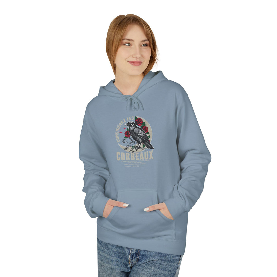 Une femme porte un sweat à capuche bleu clair avec une illustration de corbeau et de roses.