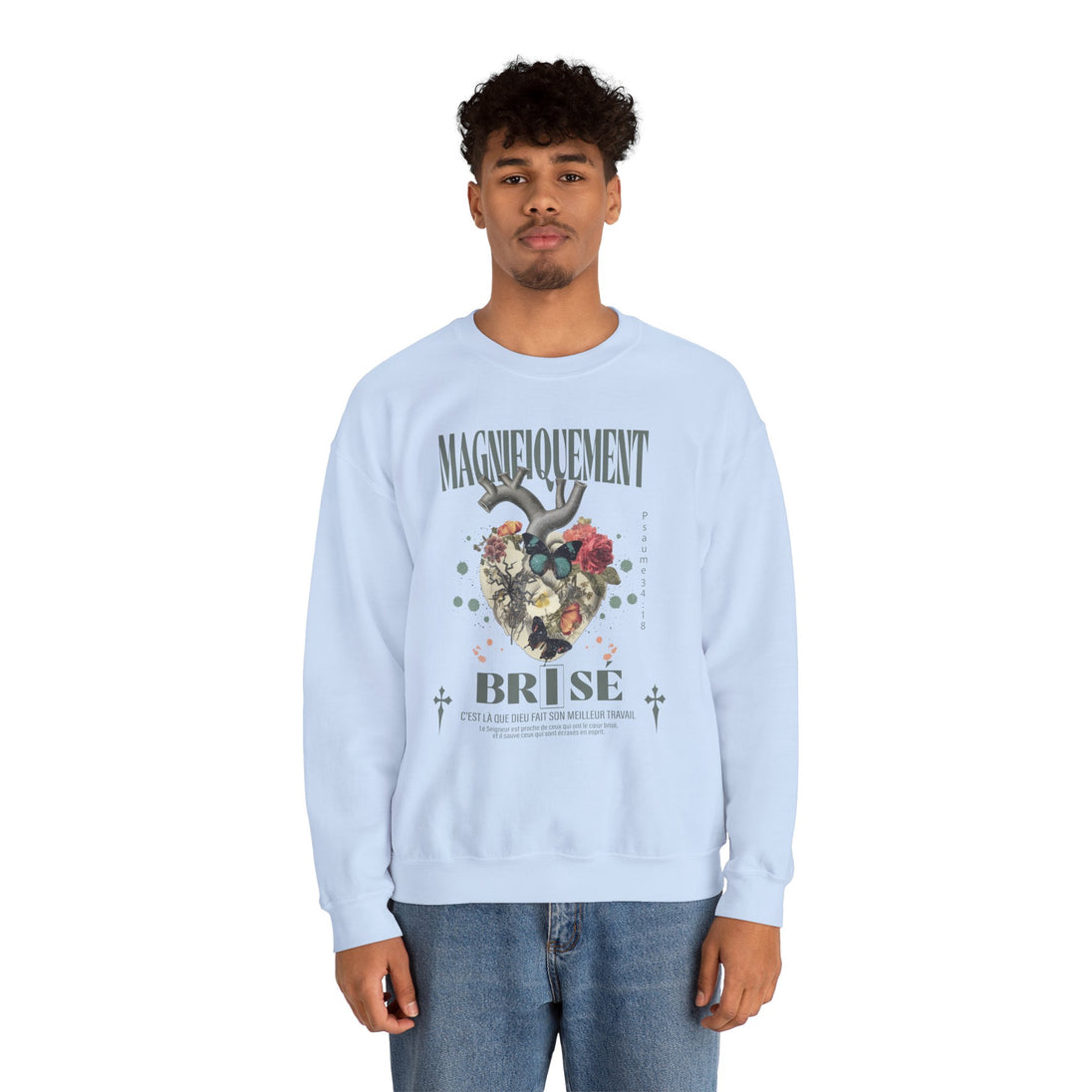 Un homme porte un sweatshirt bleu clair avec une illustration de cœur floral et du texte imprimé.