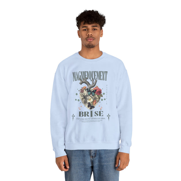Un homme porte un sweatshirt bleu clair avec une illustration de cœur floral et du texte imprimé.