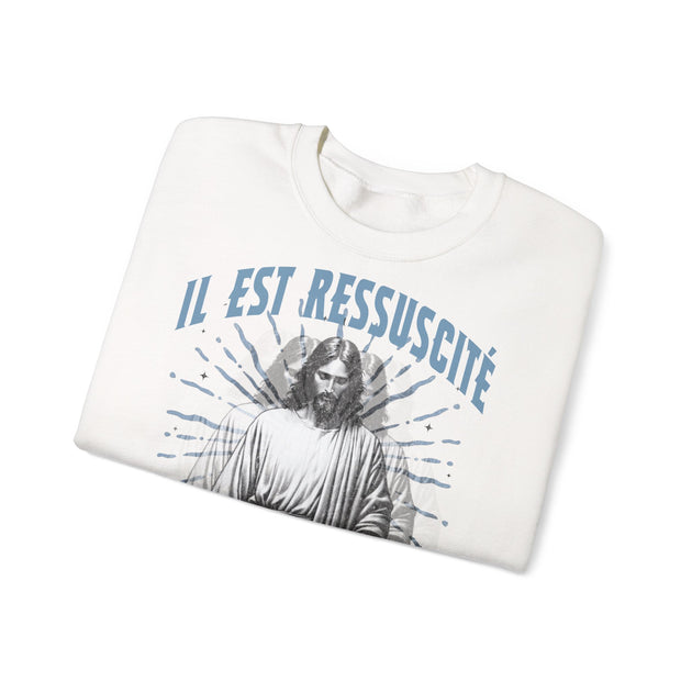 Sweatshirt blanc plié avec l'inscription Il est ressuscité et une illustration de Jésus.
