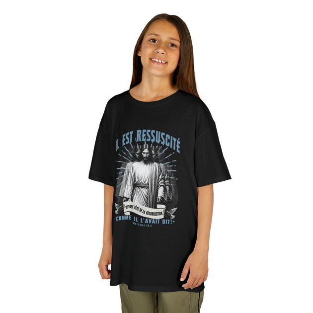 Une jeune fille porte un t-shirt noir avec une illustration religieuse et le texte Il est ressuscité.