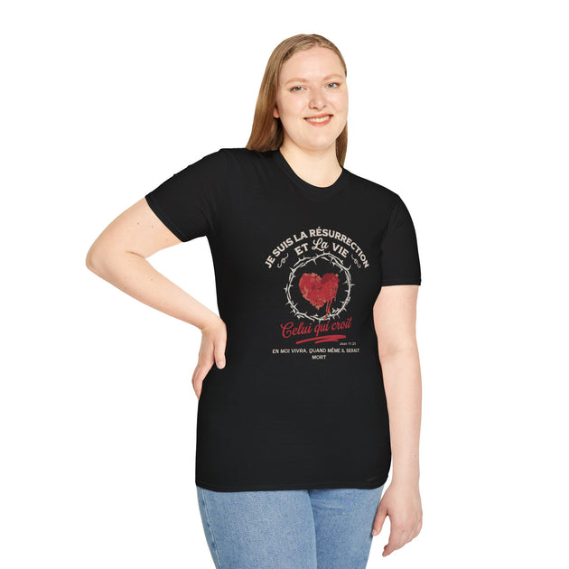 Une femme porte un t-shirt noir avec un motif religieux représentant un cœur et une couronne.