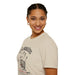 Une femme porte un t-shirt beige en coton avec une empreinte de main et un texte religieux.