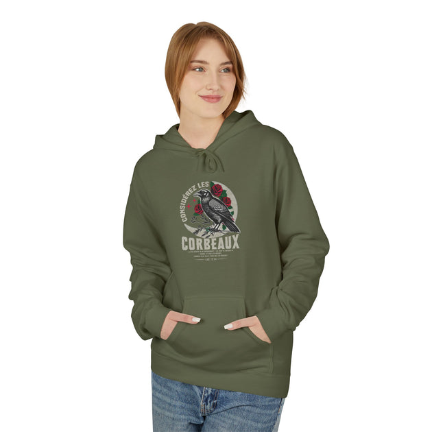Une femme porte un sweat à capuche vert olive orné d'un motif de corbeau et de roses.