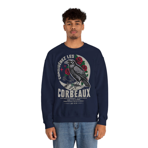 Un homme porte un sweatshirt bleu marine avec une illustration de corbeau et des roses.