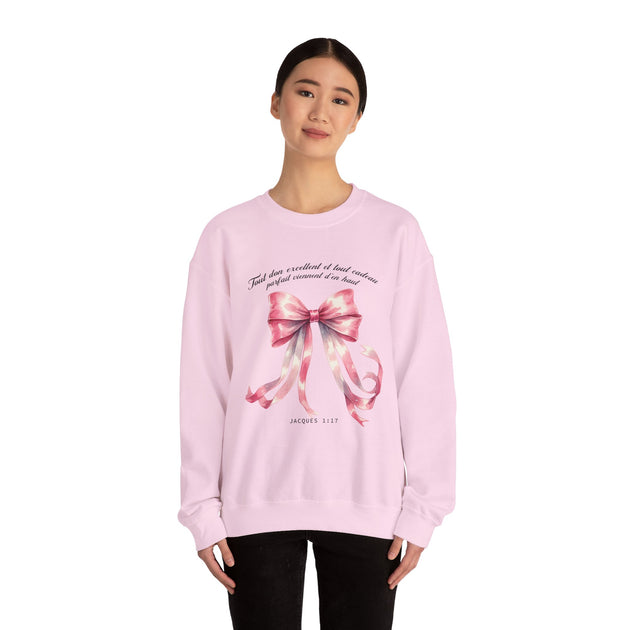 Une femme porte un sweatshirt rose pâle orné d'un ruban aquarelle et du verset Jacques 1:17.