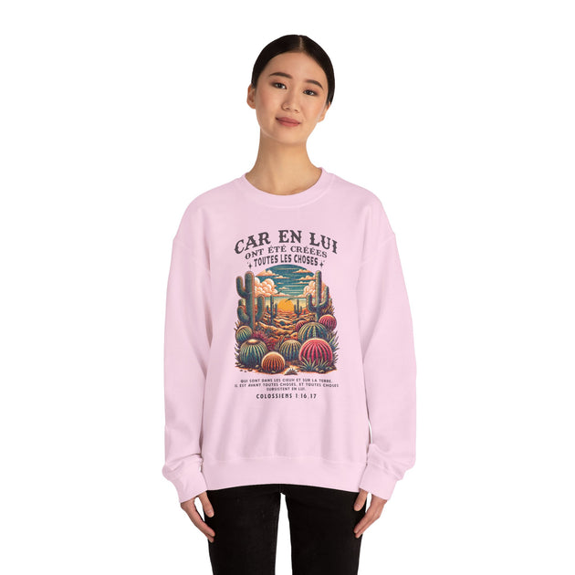 Une femme porte un sweat-shirt rose pâle avec une illustration de cactus et un texte religieux.