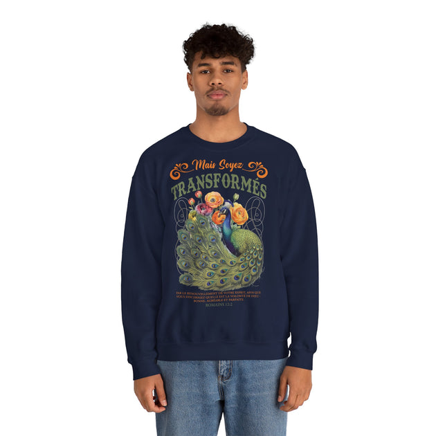 Un homme porte un sweat-shirt bleu marine avec un paon et le texte Mais soyez transformés.