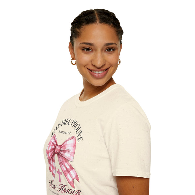 Une femme porte un t-shirt beige orné d'un nœud vichy rose et du texte Mais Dieu prouve son amour.