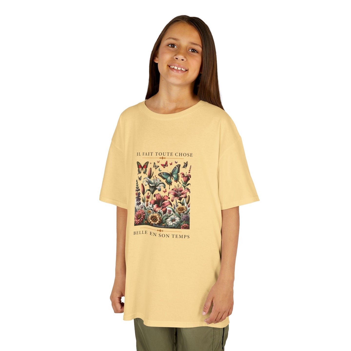 Une jeune fille porte un t-shirt jaune pâle orné d'un motif floral et de papillons.