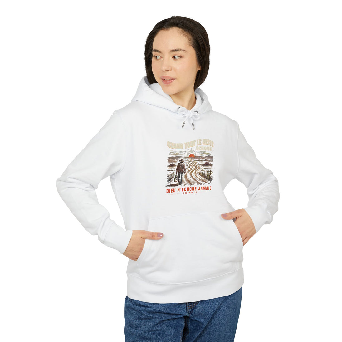 Une femme porte un sweat à capuche blanc avec une illustration de voyageur et un texte religieux.