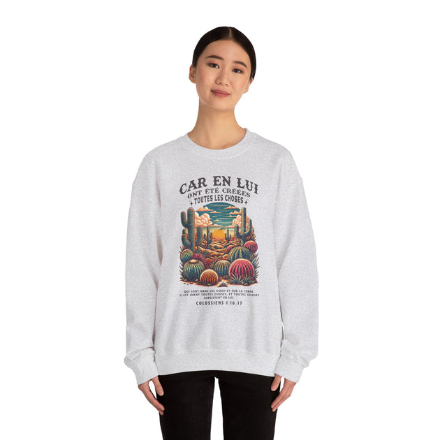 Une femme porte un sweat-shirt gris chiné orné d'une illustration de cactus et d'un texte biblique.