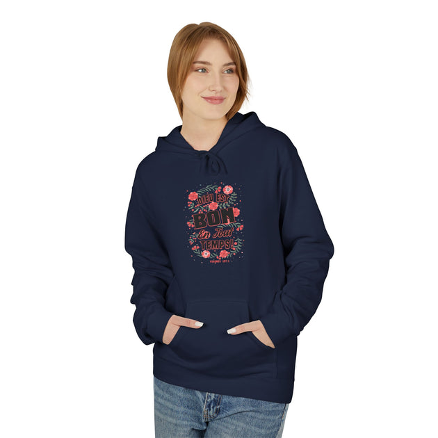 Une femme porte un sweat à capuche bleu marine avec un motif floral et le texte Dieu est bon.