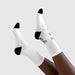 Paire de chaussettes blanches mi-mollet avec talons et pointes noirs, ornées d'un motif illustré.