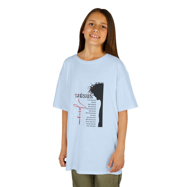 Une enfant porte un t-shirt bleu clair orné d'une illustration de Jésus et de textes religieux.
