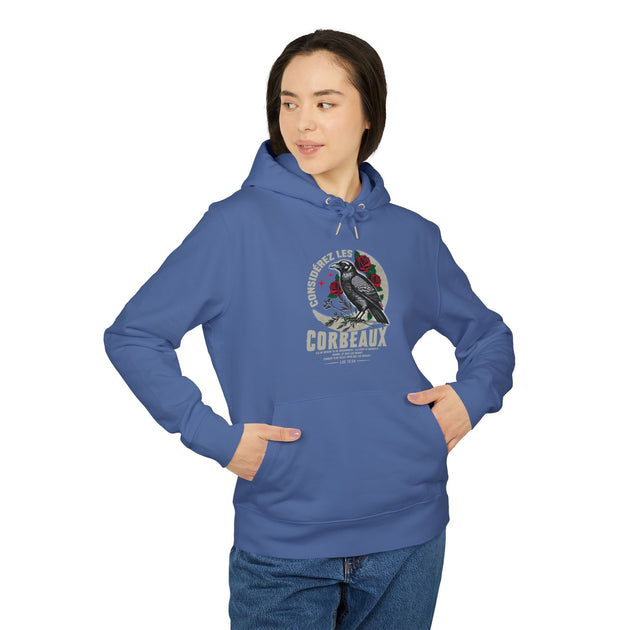 Une femme porte un sweat à capuche bleu avec une illustration de corbeau et des roses.