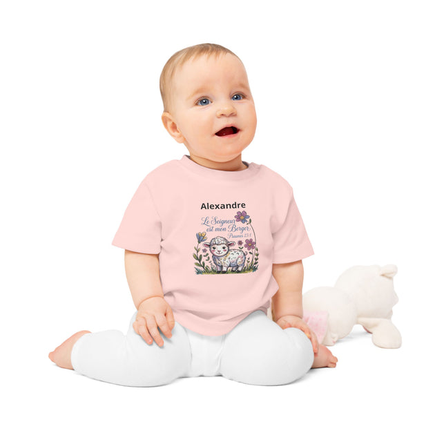 Bébé porte un t-shirt rose en coton bio avec un motif d'agneau et l'inscription Le Seigneur est mon Berger.