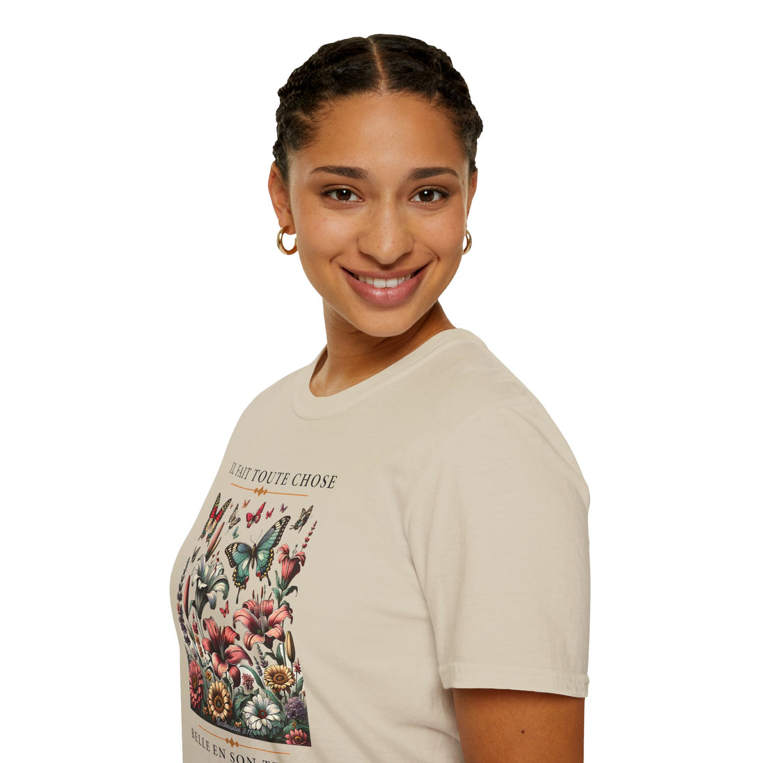 Une femme porte un t-shirt beige orné d'un motif floral et de papillons avec un texte inspirant.