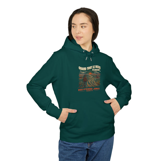 Une femme porte un sweat à capuche vert foncé avec une illustration de paysage et du texte.