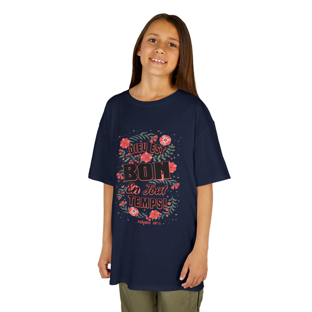 Une jeune fille porte un t-shirt bleu marine avec un motif floral et le texte Dieu est bon.