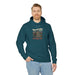 Un homme porte un sweat à capuche bleu pétrole avec une illustration de paysage et du texte.