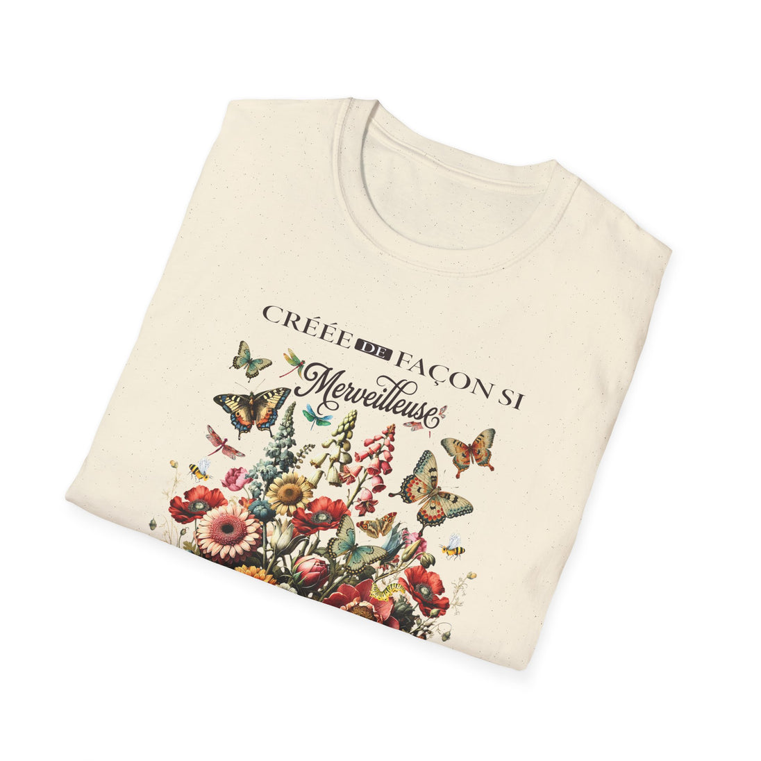T-shirt beige plié avec une illustration de fleurs et de papillons et le texte Créée de façon.