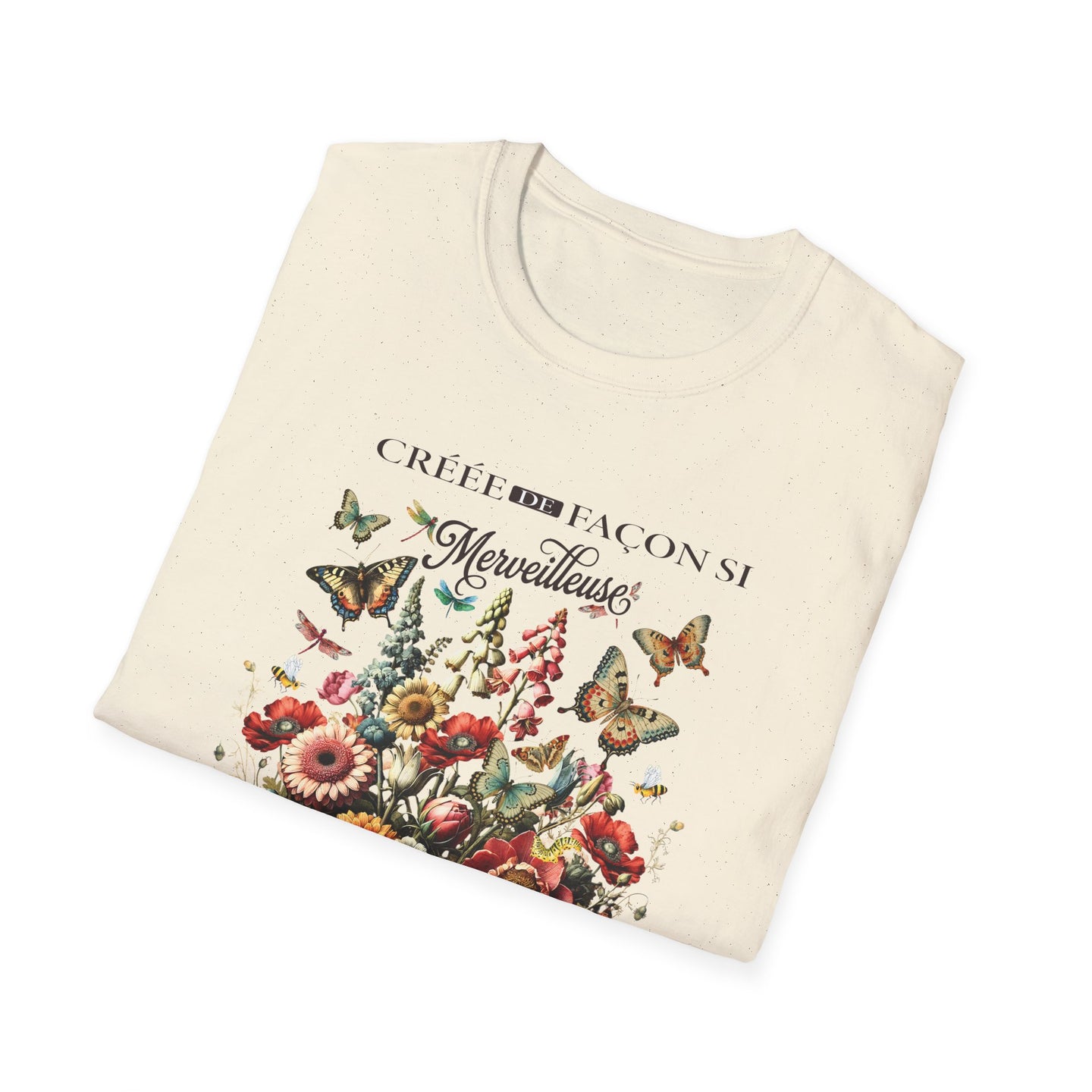 T-shirt beige plié avec une illustration de fleurs et de papillons et le texte Créée de façon.