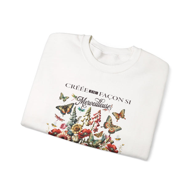 Sweat-shirt blanc plié avec une illustration de fleurs et de papillons et le texte Créée de façon.
