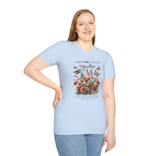 Une femme porte un t-shirt bleu clair orné d'un motif floral, de papillons et d'un texte religieux.