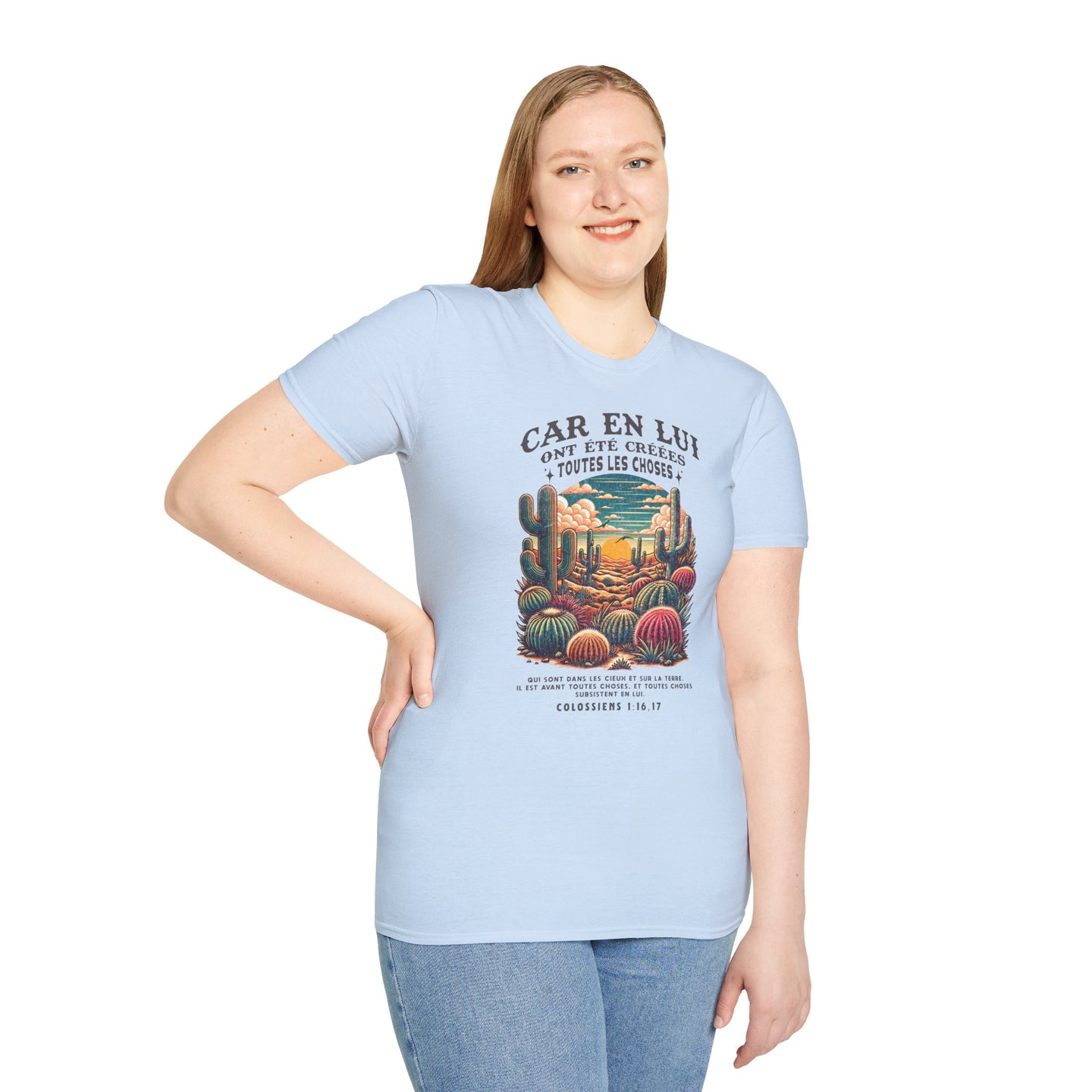 Une femme porte un t-shirt bleu clair avec une illustration de désert et un verset biblique.