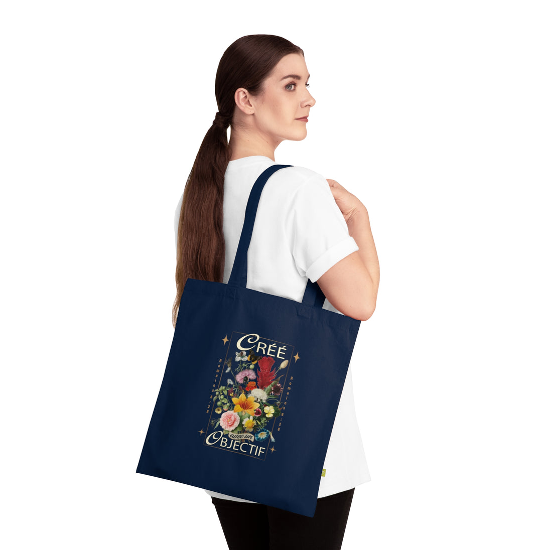 Une femme porte sur l'épaule un sac fourre-tout bleu marine orné d'un motif floral et du texte Créé.