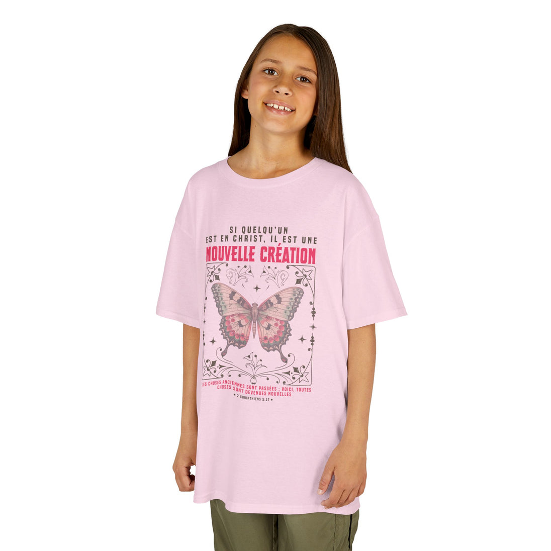 Une jeune fille porte un t-shirt rose orné d'un papillon et d'un verset biblique en français.